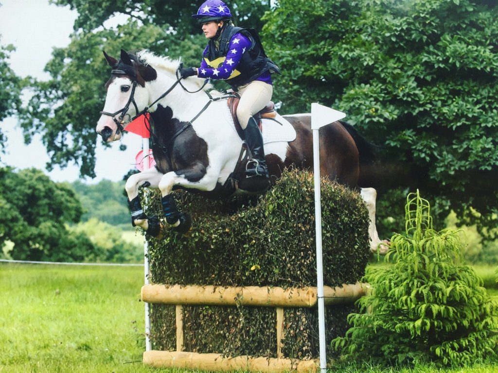 Megan Elphick going over a brush fence on a cross country course on her coloured horse Lara