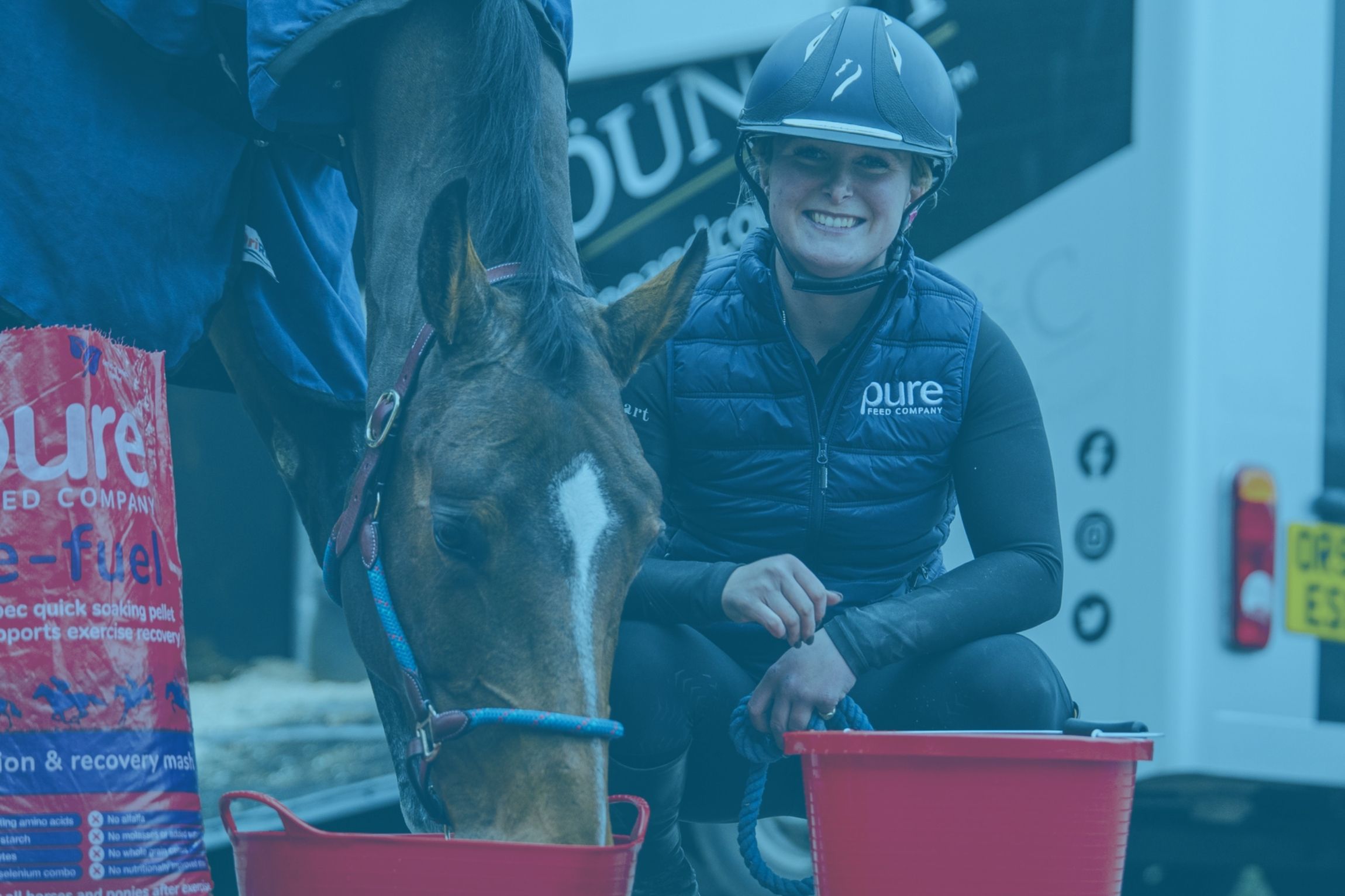 Smiling equestrian beside her horse enjoying a feed from Pure Feed Company